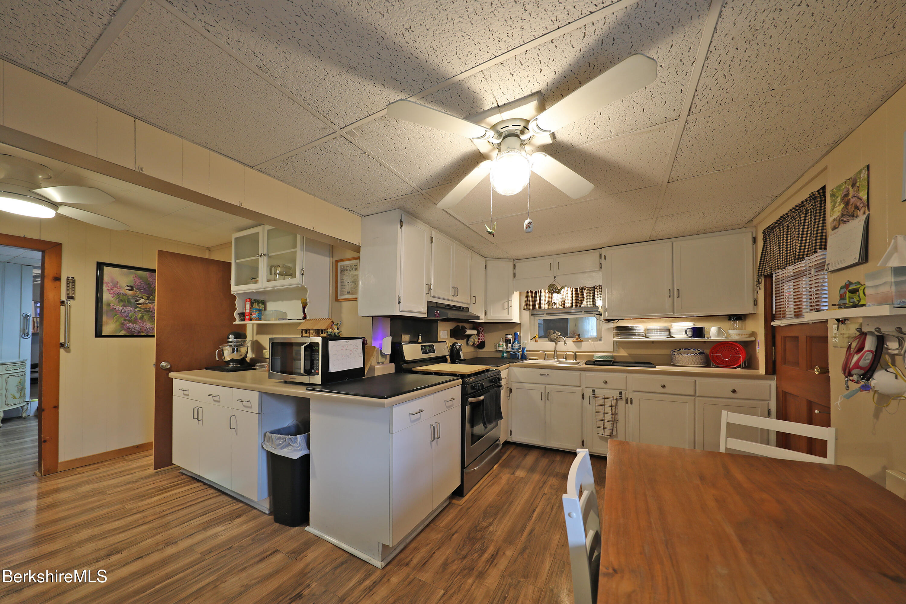 735 Cape Street Lee, MA 01238 - Photo 8 of 23 a kitchen with stainless steel appliances a stove top oven a sink dishwasher and white cabinets with wooden floor