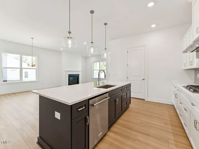 a large kitchen with kitchen island a sink a stove a wooden floor and a window