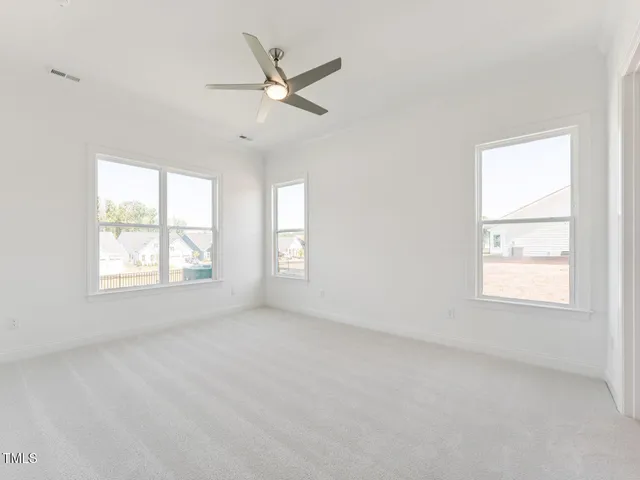 an empty room with windows and fan