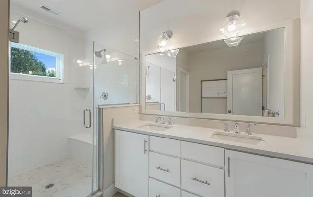 a bathroom with a double vanity sink mirror and shower