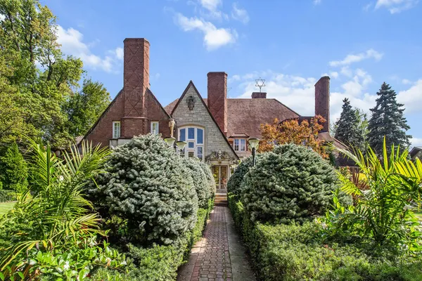 a front view of a house with a yard and fountain in middle