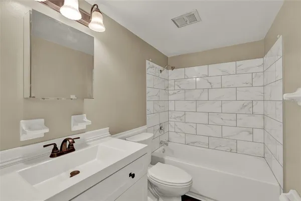 a bathroom with a bathtub shower sink vanity and toilet