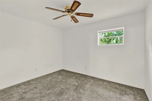 an empty room with a window and a fan