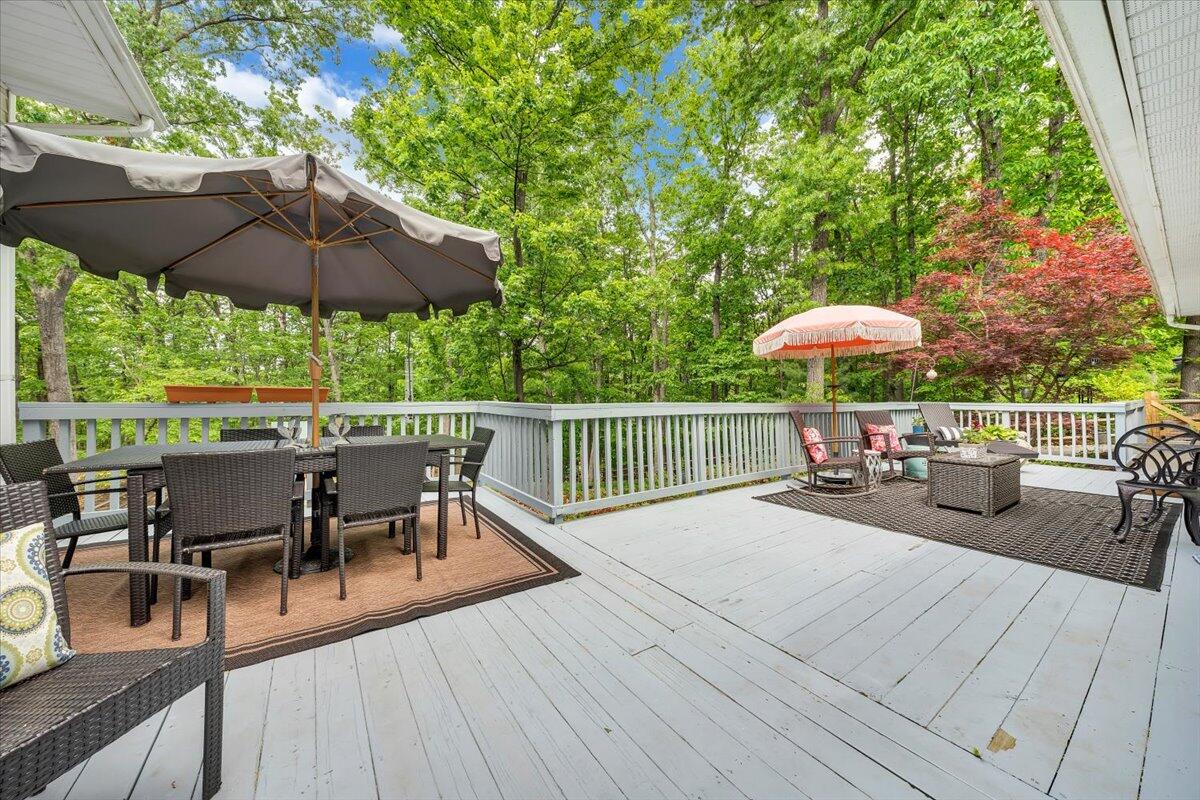 5249 Falcon Ridge Road Roanoke, VA 24018 - Photo 48 of 58 a view of a roof deck with table and chairs under an umbrella with wooden floor