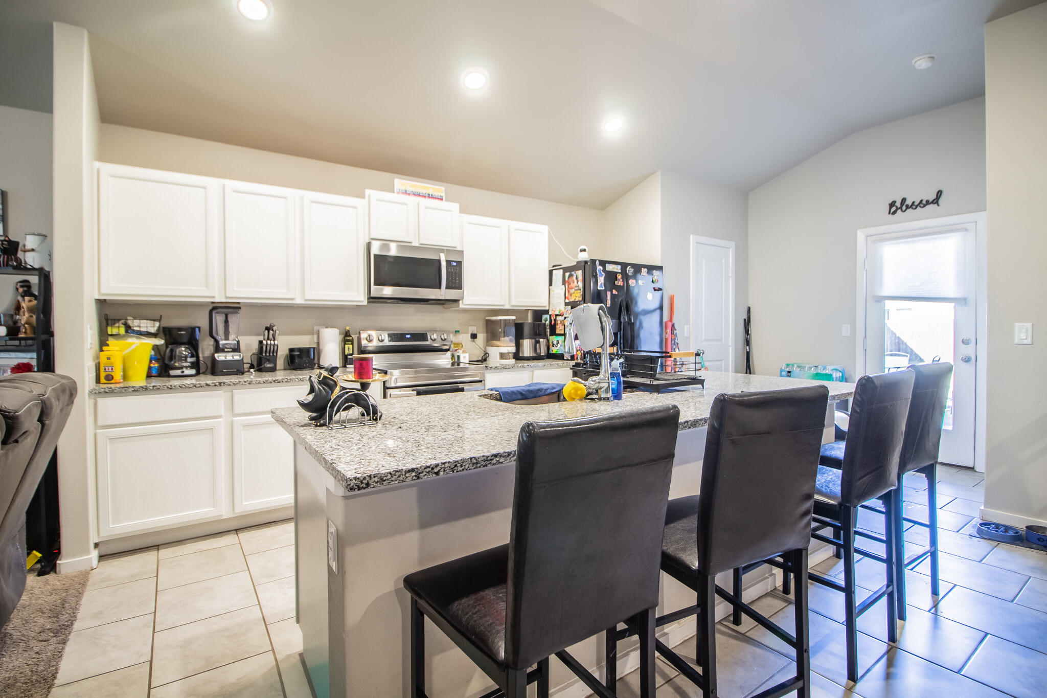 2908 Waverly Avenue Lubbock, TX 79407 - Photo 7 of 22 a kitchen with stainless steel appliances granite countertop a stove a sink dishwasher a dining table and chairs with wooden floor