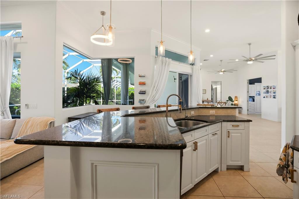 80 Delbrook Way Marco Island, FL 34145 - Photo 49 of 49 Kitchen featuring dark stone counters, open floor plan, white cabinets, an island with sink, and light tile patterned floors