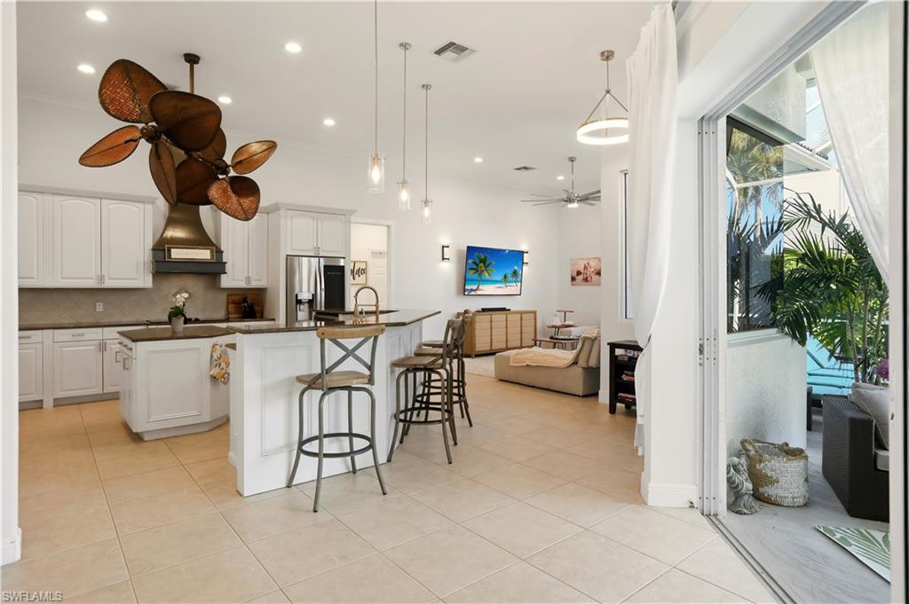 80 Delbrook Way Marco Island, FL 34145 - Photo 12 of 49 Kitchen featuring a kitchen island with sink, ceiling fan, white cabinetry, pendant lighting, and a kitchen bar