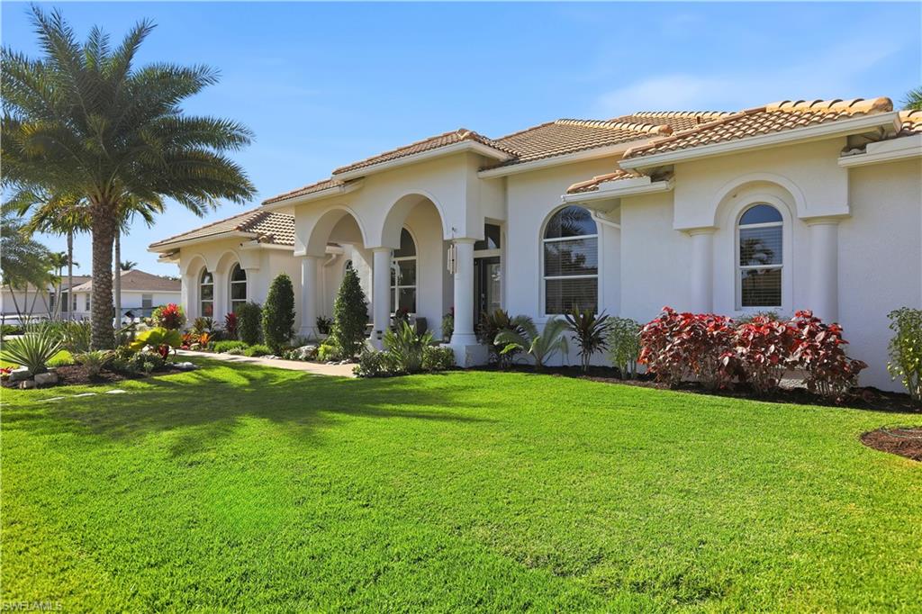 80 Delbrook Way Marco Island, FL 34145 - Photo 2 of 49 View of property exterior featuring a yard, stucco siding, and a tiled roof