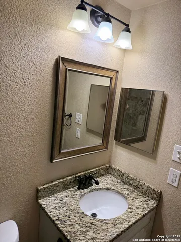 a bathroom with a granite countertop sink and a mirror