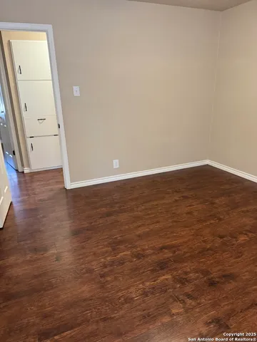 an empty room with wooden floor and mirror