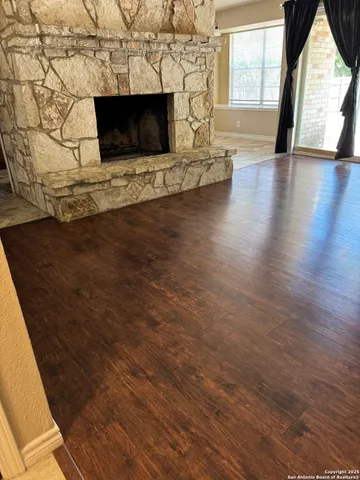 a living room with a fireplace wooden floor and a large window