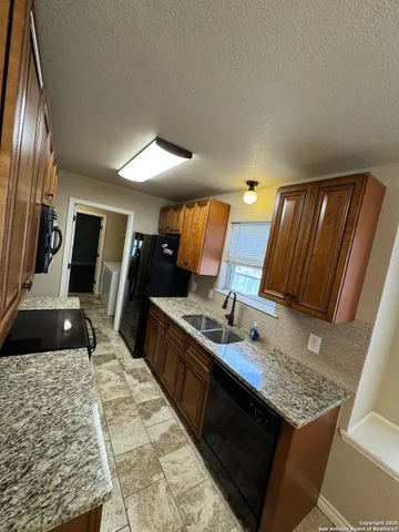 a living room with stainless steel appliances furniture a rug and a view of kitchen
