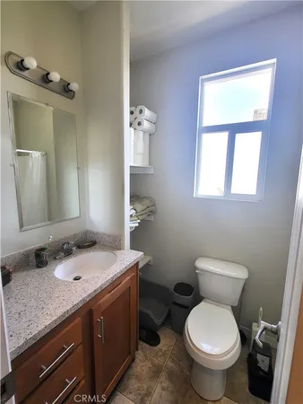 a bathroom with a granite countertop toilet a sink and mirror