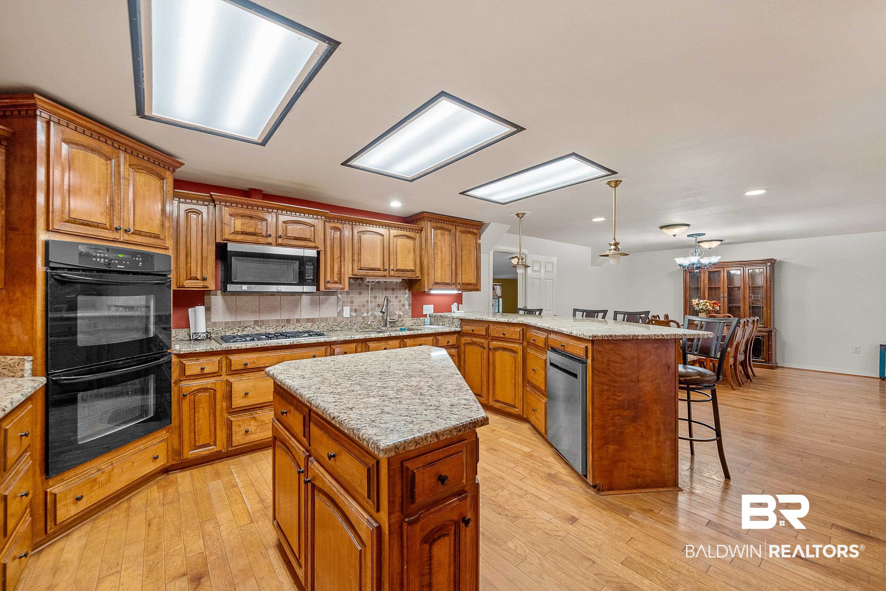 11528 Whitehouse Fork Road Bay Minette, AL 36507 - Photo 12 of 37 Kitchen featuring brown cabinets, pendant lighting, a kitchen island, stainless steel appliances, and tasteful backsplash