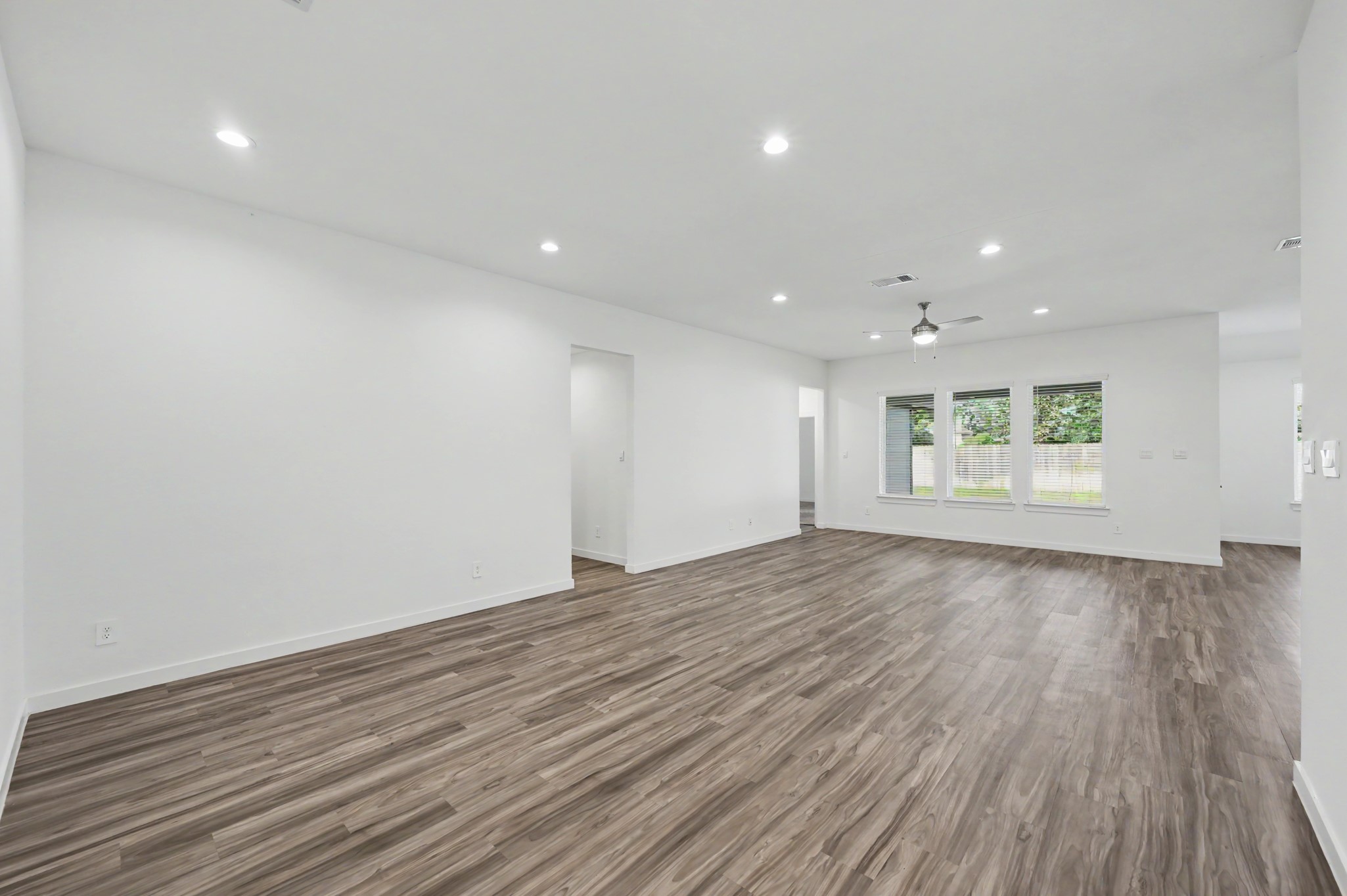 14162 Primrose Ridge Lane Conroe, TX 77384 - Photo 9 of 48 Spacious open-concept living area with sleek wood flooring, abundant natural light from large windows, and modern recessed lighting.
