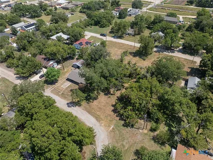 an aerial view of residential house with outdoor space and trees all around