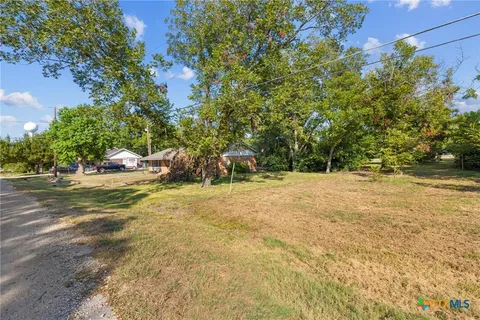 a view of a yard with plants and trees