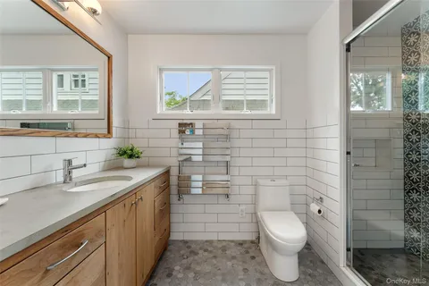 a bathroom with a granite countertop toilet a sink a window and shower