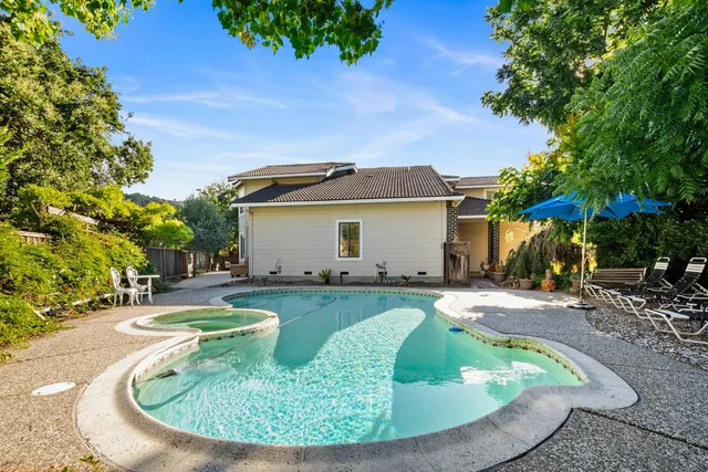 a view of a house with backyard sitting area and covered with trees