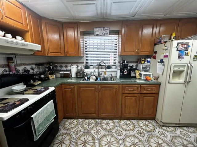 a kitchen with stainless steel appliances granite countertop a refrigerator a sink and wooden cabinets