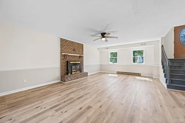 an empty room with wooden floor fireplace and windows