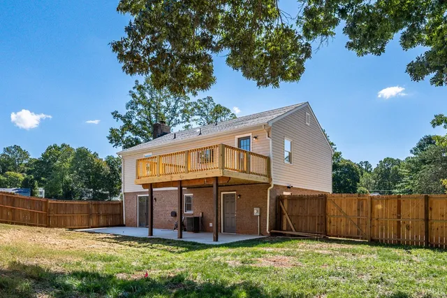 a view of a house with a yard plants and large tree