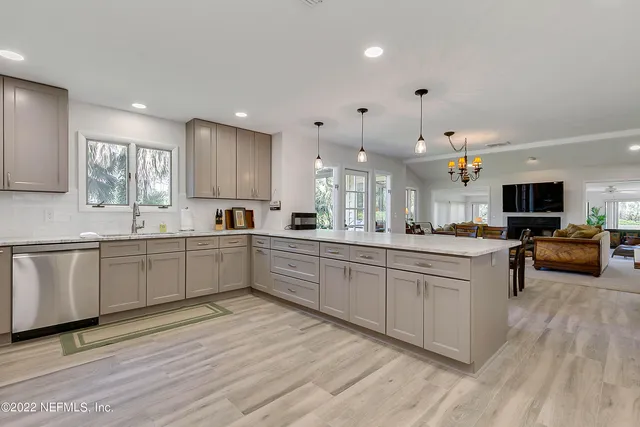 a large kitchen with stainless steel appliances kitchen island granite countertop a large counter top a sink dishwasher and a stove with wooden floor
