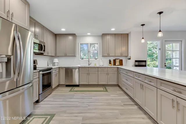 a large kitchen with stainless steel appliances lots of counter top space cabinets and a window
