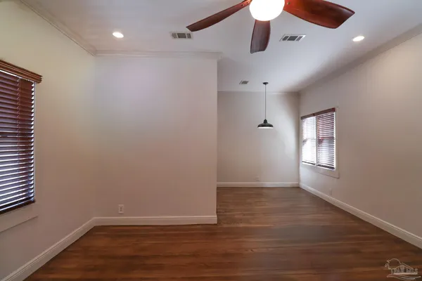 an empty room with wooden floor chandelier fan and windows