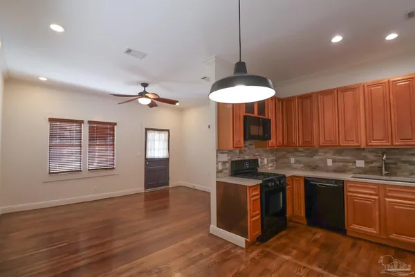 a kitchen with stainless steel appliances granite countertop a sink a stove and a wooden floors