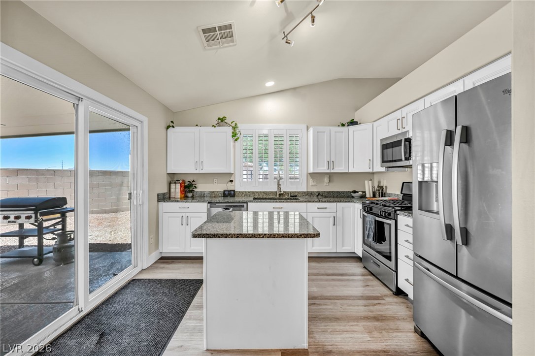 1234 Sunfire Street Henderson, NV 89014 - Photo 12 of 40 Culinary delights await in this bright kitchen with a convenient island and sliding glass door access to the outdoor space.