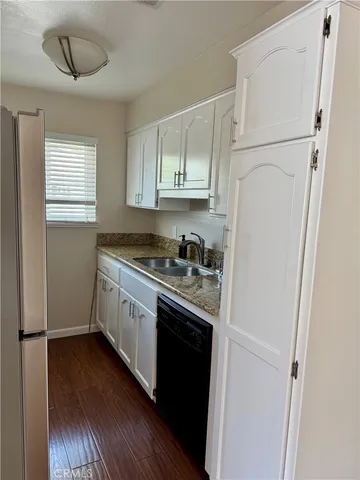 a kitchen with stainless steel appliances granite countertop a refrigerator a sink dishwasher a stove and white countertops with wooden floor