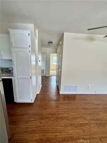 a view of a room with wooden floor and a refrigerator