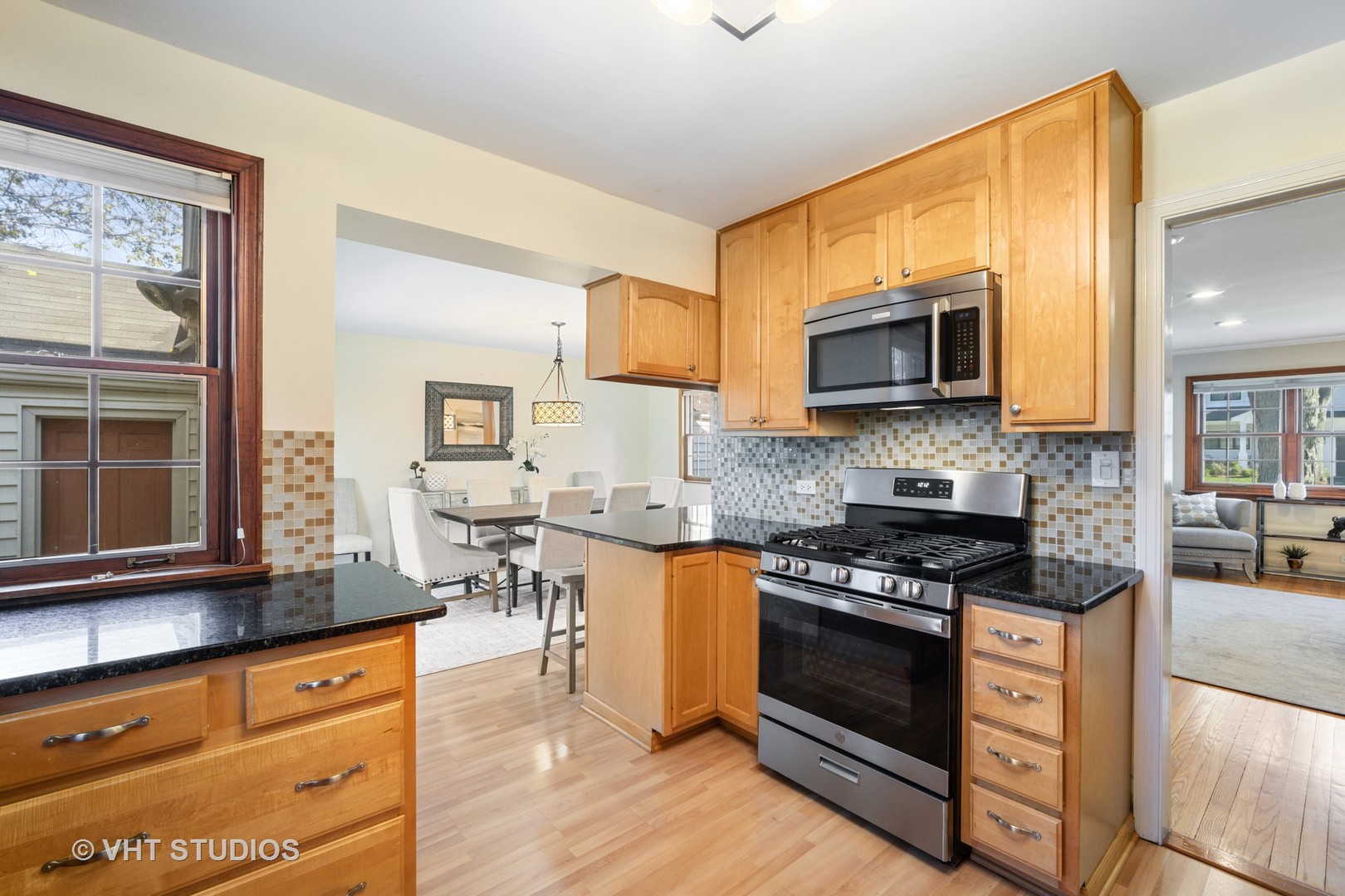 932 Echo Lane Glenview, IL 60025 - Photo 6 of 18 a kitchen with stainless steel appliances kitchen island granite countertop a stove top oven a sink dishwasher a dining table and chairs with wooden floor