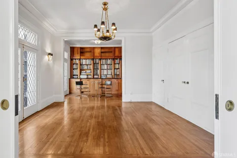 a view of an empty room with window and wooden floor