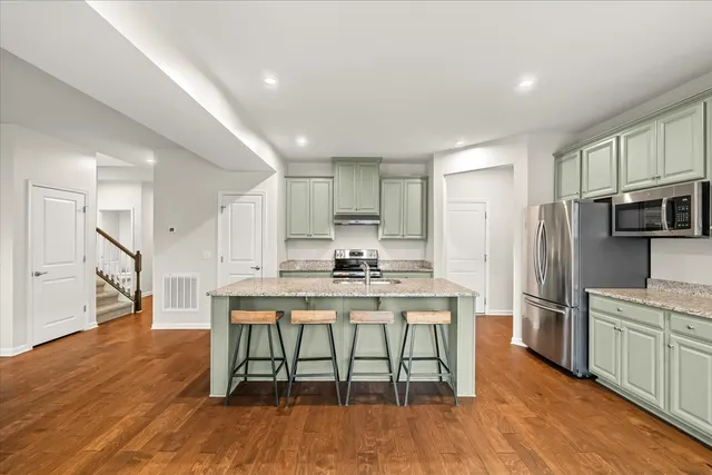 a kitchen with stainless steel appliances a table chairs refrigerator and microwave