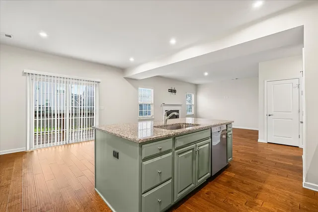 a kitchen with stainless steel appliances granite countertop a stove a sink and a large refrigerator with wooden floor