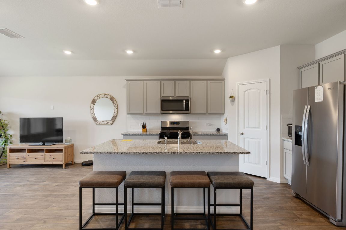 a kitchen with microwave a refrigerator and chairs