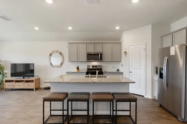 a kitchen with microwave a refrigerator and chairs
