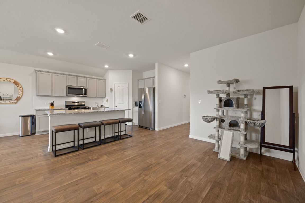 13908 Mamie Eisenhower Road Manor, TX 78653 - Photo 10 of 23 a living room with stainless steel appliances kitchen island granite countertop a wooden floor and white cabinets