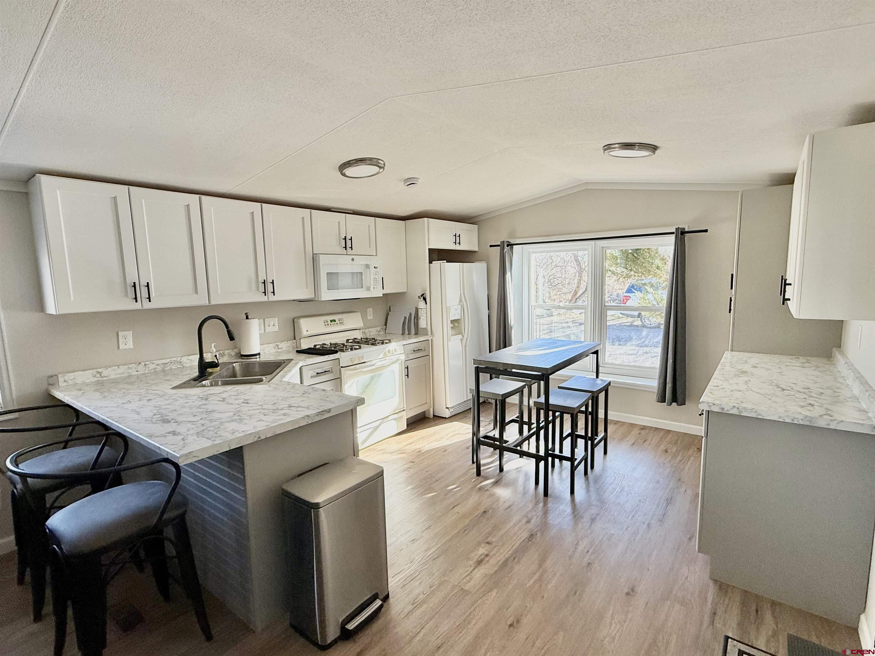 676 Highway 50, Unit SPACE 44 Delta, CO 81416 - Photo 6 of 29 a kitchen with a table chairs a sink dishwasher stove and cabinets with wooden floor