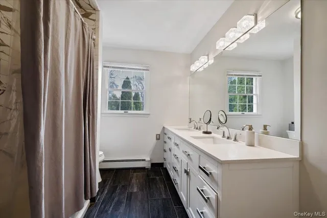 a spacious bathroom with a double vanity sink a mirror and a shower