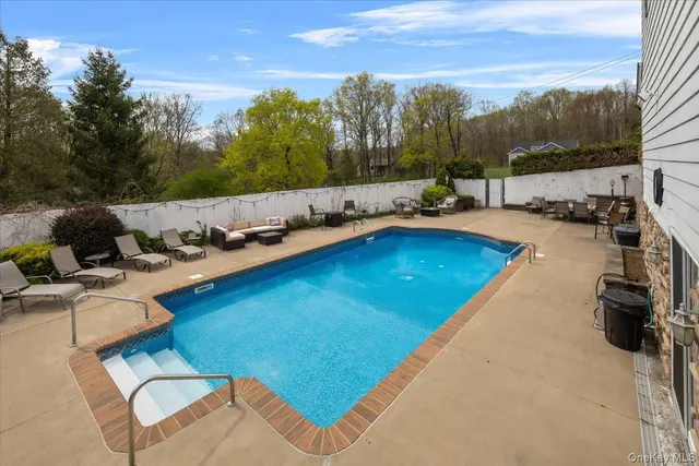 a view of swimming pool with seating area and trees in the background