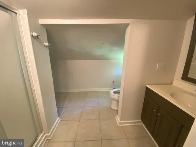 a bathroom with a granite countertop sink and a toilet