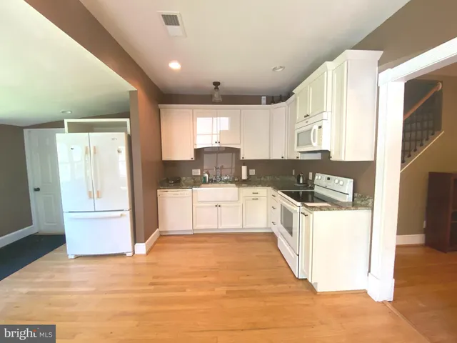 a large kitchen with stainless steel appliances granite countertop a stove a sink and white cabinets