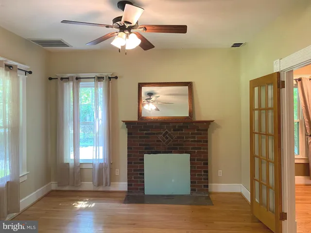 a living room with a fireplace windows and a ceiling fan