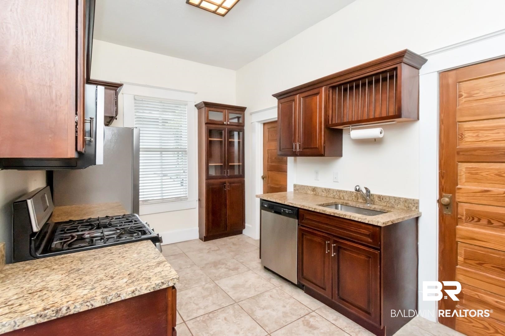 14 Kenneth Street Mobile, AL 36607 - Photo 9 of 32 Kitchen with appliances with stainless steel finishes, light stone counters, light tile patterned floors, and glass insert cabinets