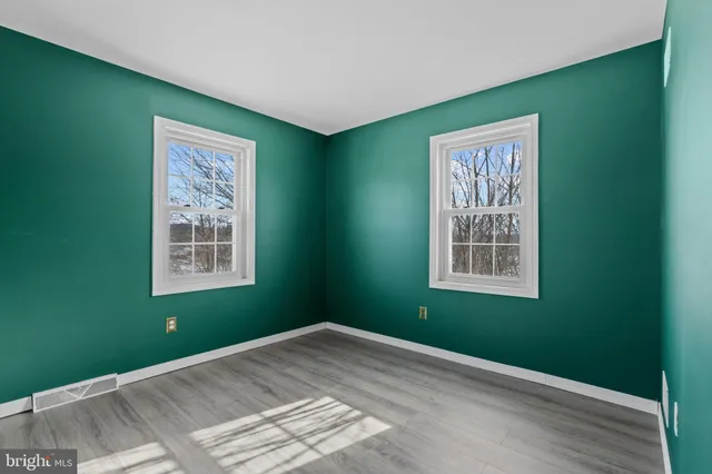 a view of a big yard with swimming pool and trees in the background