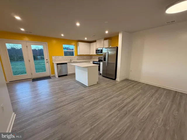 an open kitchen with wooden floor and stainless steel appliances