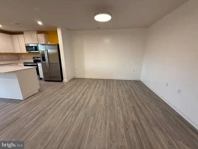 a view of kitchen with cabinets wooden floor and stainless steel appliances